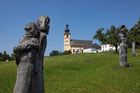 Wooden sculptures at the Stations of the Cross on Kirchberg with parish church