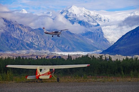 Two small bush planes in front of huge glaciers