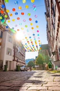 Colourful lanterns hanging in alleyway alley between half-timbered houses