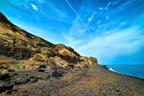 Dramatic landscape of blue sea or ocean waves rolling on rocky volcanic beach on cloudy day. Blue sky