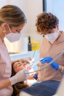 Technician examining the mouth of a woman reclining on chair in a dental clinic