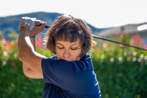 Front View on a Female Golfer Making a Golf Swing in a Sunny Day in Switzerland