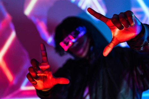 Studio portrait with purple and blue neon lights of a futuristic man picturing the future gesturing with hands