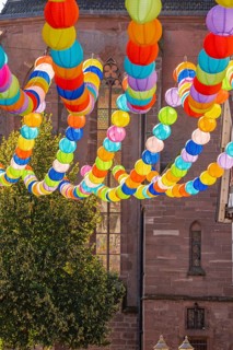Colourful lanterns hanging in alleyway alley between half-timbered houses