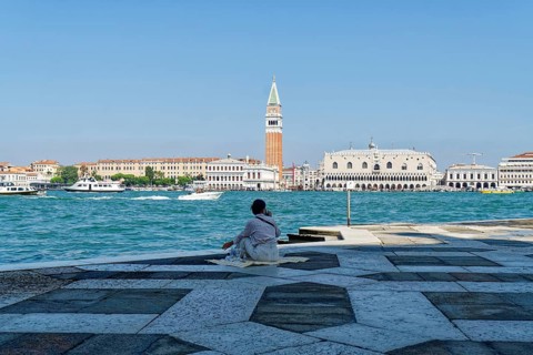 Woman having a picnic in the square in front of the church of San Giorgio Maggiore on the Giudecca Canal with a view of the Doge's Palace