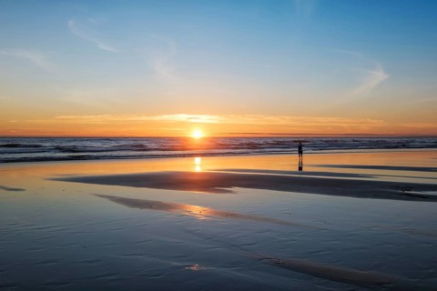 Atlantic ocean sunset with photographer silhouette taking images of surging waves at Fonte da Telha beach