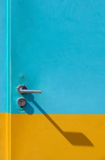 Yellow-cyan iron door with lock and door handle with shadow