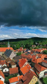 Aerial view of Koenigsberg in Bavaria. The city is surrounded by hills and forests. The sky is cloudy and dark