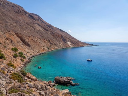 Sailboat anchored in a bay next to the E4 long-distance footpath along the rocky coast to Chora Sfakion