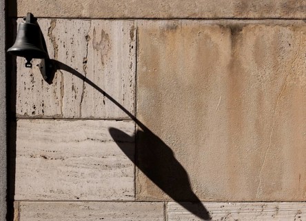Old Door Bell with Shadow on a Stone Wall with Sunlight in Switzerland