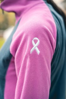 Side view of a woman wearing a sweatshirt with an embroidered cancer awareness ribbon. Vertical Shot
