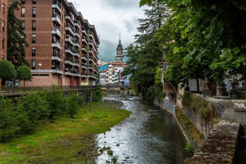 Traditional houses in the town of Azkoitia next to the Urola river and Church of Santa Maria La Real in the background