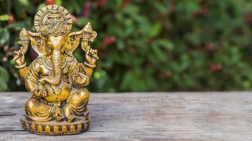 Ganesha statue sitting in meditating yoga pose on a trunk. Copy space
