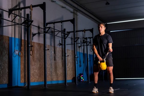 Dark and artistic portrait with artificial lights of a sportive disabled man training with a kettlebell