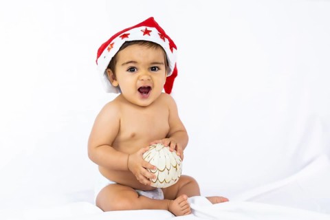 A baby boy with a red Christmas hat on a white background