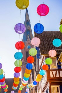 Colourful lanterns hanging in alleyway alley between half-timbered houses