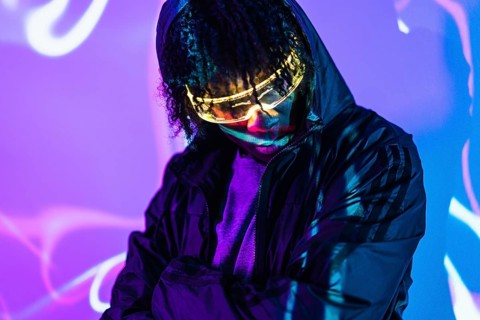 Studio portrait with purple and blue neon lights of a man in a future space using Virtual realty goggles