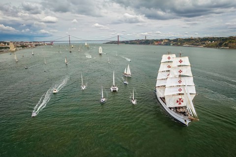 Aerial drone view of tall ships with sails sailing in Tagus river towards the Atlantic ocean in Lisbon