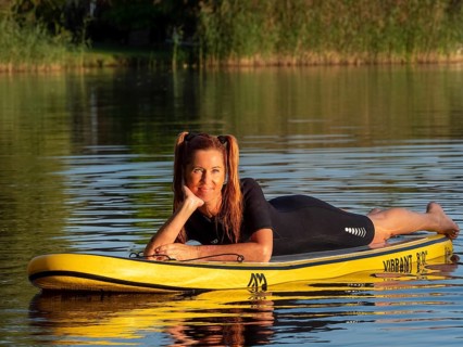 Woman lying relaxed on standup paddle board in lake