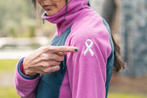 Mid adult woman pointing to an embroidered cancer awareness ribbon with her finger on her sweatshirt