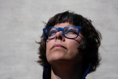 Headshot on a Elegant Woman with Eyeglasses and Looking Up and Leaning on a Concrete Wall in a Sunny Day in Switzerland