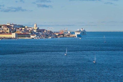 View of Lisbon over Tagus river from Almada with yachts tourist boats and moored cruise liner on sunset. Lisbon