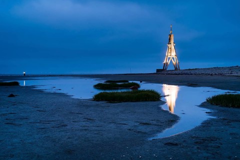 Kugelbake illuminated with water reflection at dusk