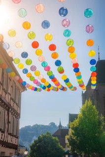 Colourful lanterns hanging in alleyway alley between half-timbered houses