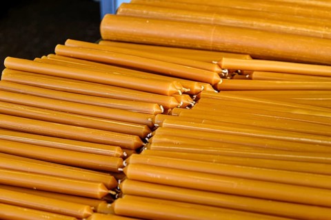 Pile of new yellow wax candles used in churches