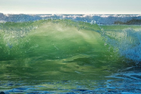 Breaking ocean wave on sunset backlit with sun. Fonte da Telha