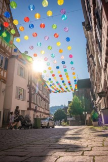 Colourful lanterns hanging in alleyway alley between half-timbered houses