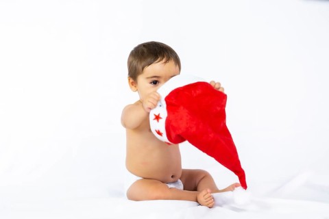 A baby boy with a red Christmas hat on a white background