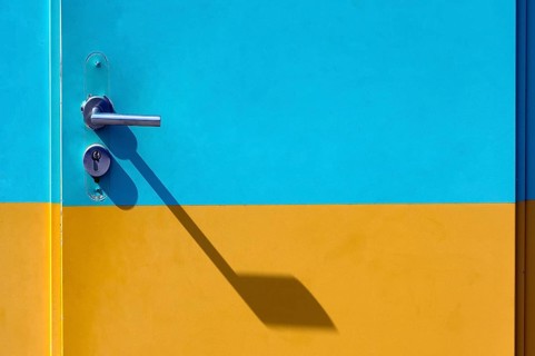 Yellow-cyan iron door with lock and door handle with shadow