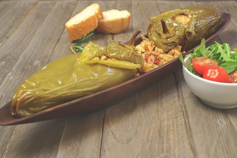 Green peppers stuffed with meat and rice in a salty tomato and lamb's lettuce sauce