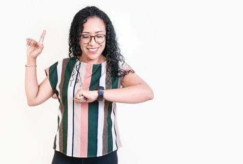 Happy young woman looking at hand watch isolated. Girl in glasses measuring time with hand watch