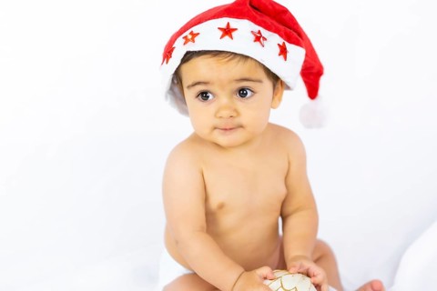 A baby boy with a red Christmas hat on a white background