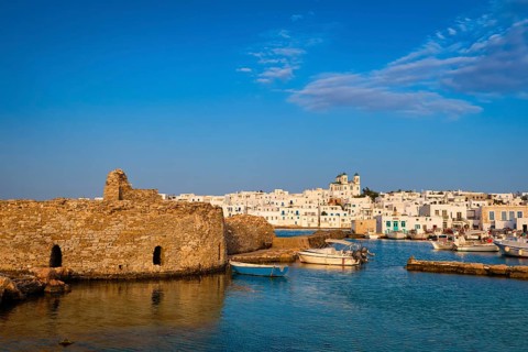 Traditional Greek whitewashed houses and church of Dormition of Mother of God as local landmark on hilltop by seafront on sunny day