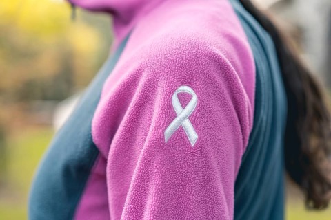 Side view of a woman wearing a sweatshirt with an embroidered cancer awarness ribbon