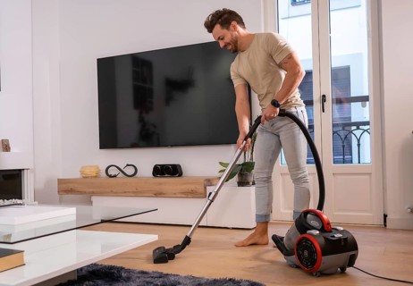 Man using vacuum to clean the living room in the house sharing housework