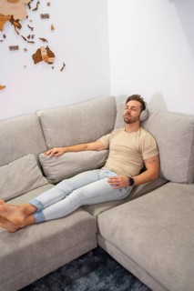 Vertical top view of a man relaxed on the sofa listening to music