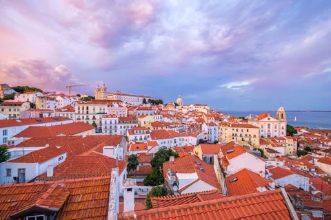 View of Lisbon famous view from Miradouro de Santa Luzia tourist viewpoint over Alfama old city district on sunset with dramatic overcast sky. Lisbon