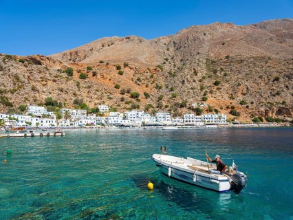 Small fishing boat in the harbour of Loutro below a rocky mountain
