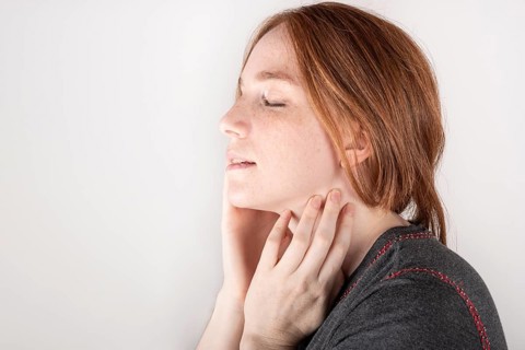 Beauty face. Smiling red haired woman touching healthy skin. Beautiful happy model with moisturized shiny fresh facial skin on white background in studio