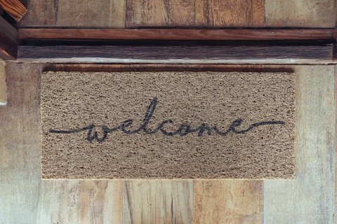 Welcome mat in front of door over wooden floor