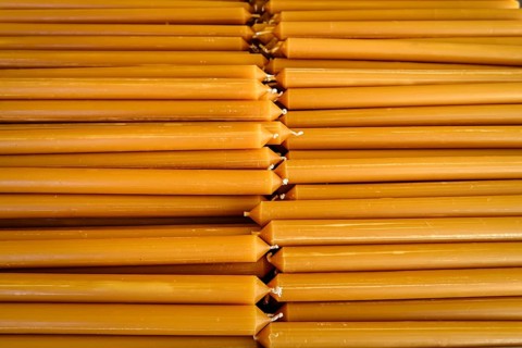Pile of new yellow wax candles used in churches