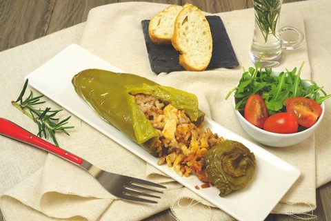 Green peppers stuffed with meat and rice in a salty tomato and lamb's lettuce sauce