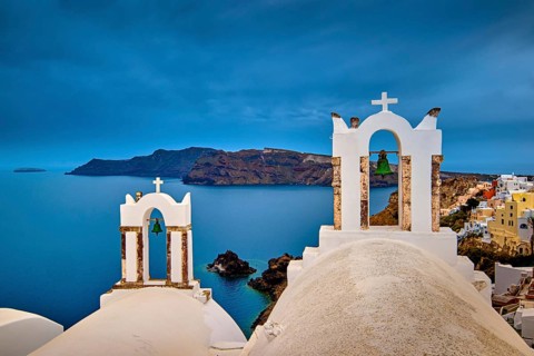 Two bell towers and dome roofs of white Greek Orthodox church in Oia village