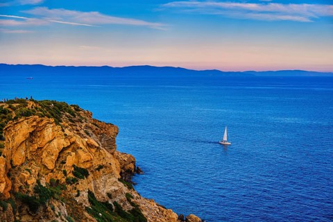 Lonely sailboat or small yacht navigating in harbour of Aegean sea near cape Sounion