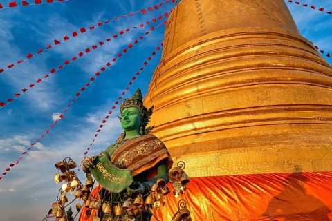 Statue of green-skinned Thai angel holding roll with message in Thai