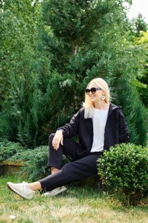 Blonde woman in fleece tracksuit sits in profile in the garden